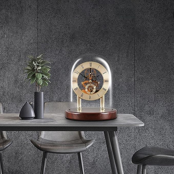 Luxurious skeleton clock with Roman numerals encased in a glass dome, glowing softly on a polished wooden base. The clock is elegantly placed on a modern gray table in a minimalist room with industrial-style chairs and a small decorative plant, creating a refined and sophisticated ambiance.