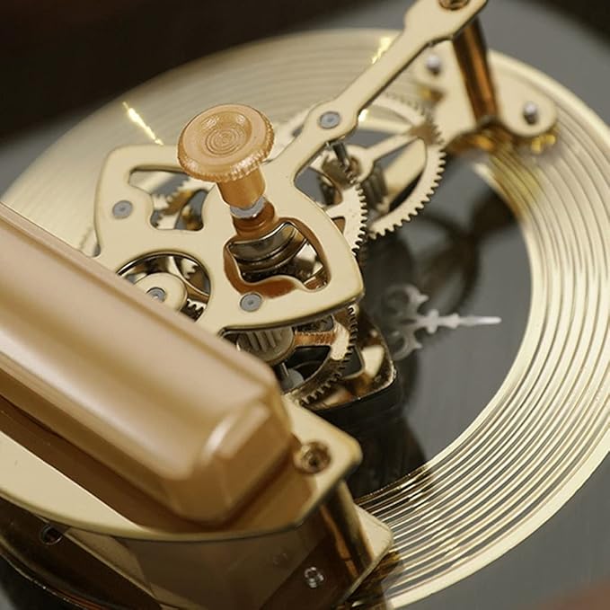 Close-up view of an intricate golden clock mechanism, showcasing finely detailed gears, a winding knob, and elegant metal components. The craftsmanship and precision of the design highlight the luxury and sophistication of the timepiece.